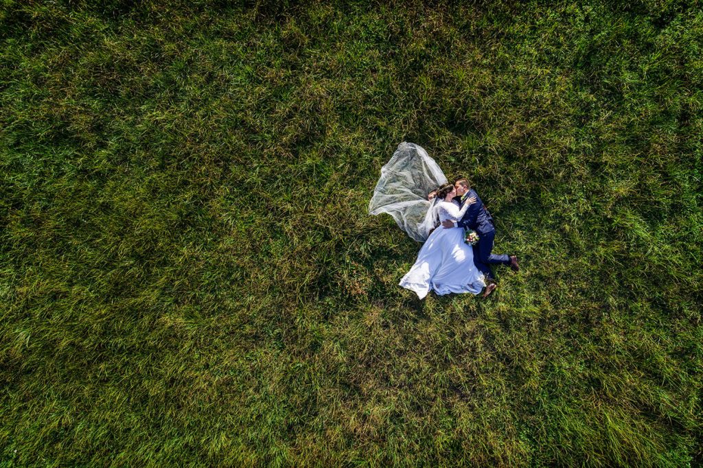 Hochzeitspaar im Gras liegend mit Drohne fotografiert