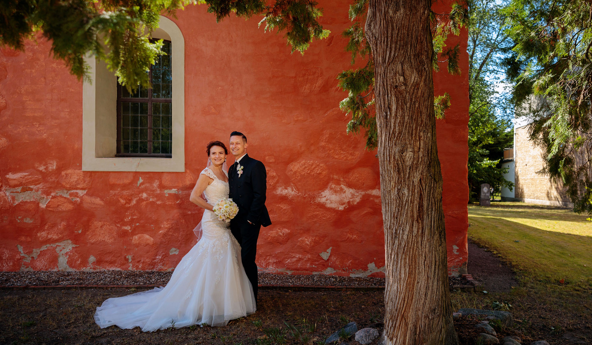 Hochzeitspaar vor der Kirche nach Trauung in Potsdam Mittelmark