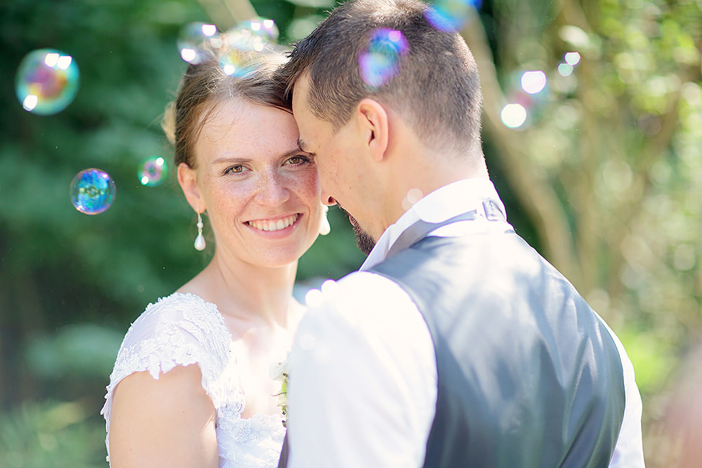 Das Brautpaar umhüllt von Seifenblasen bei den Hochzeitsfotos