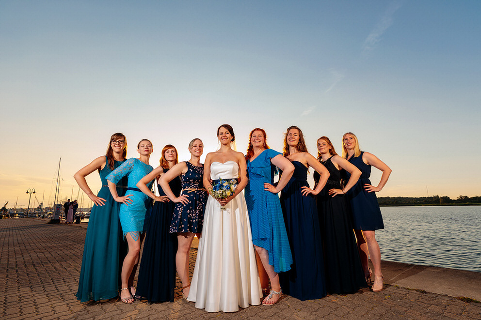 Eine Braut im Kreis ihrer Freundinnen am Meer