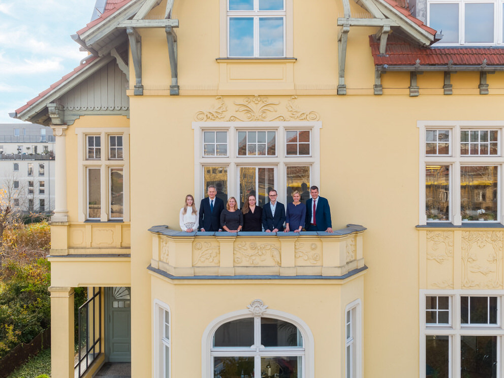 kreatives Gruppenfoto einer Kanzlei auf einem Balkon mit Drohne
